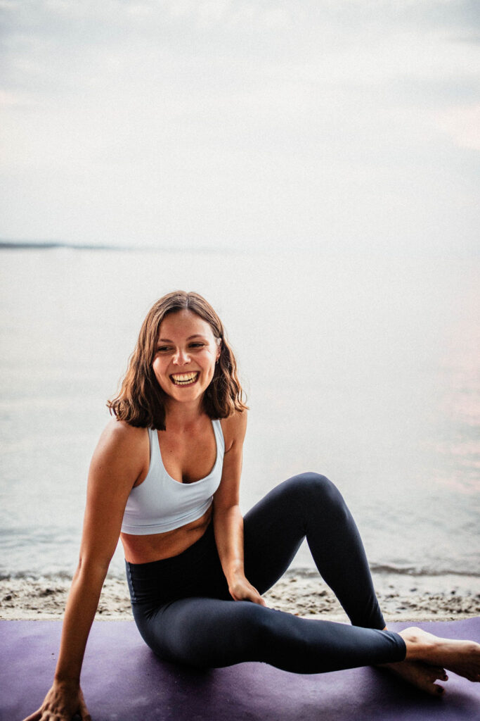 Rebecca sitzt auf der Yogamatte vor dem Bodensee